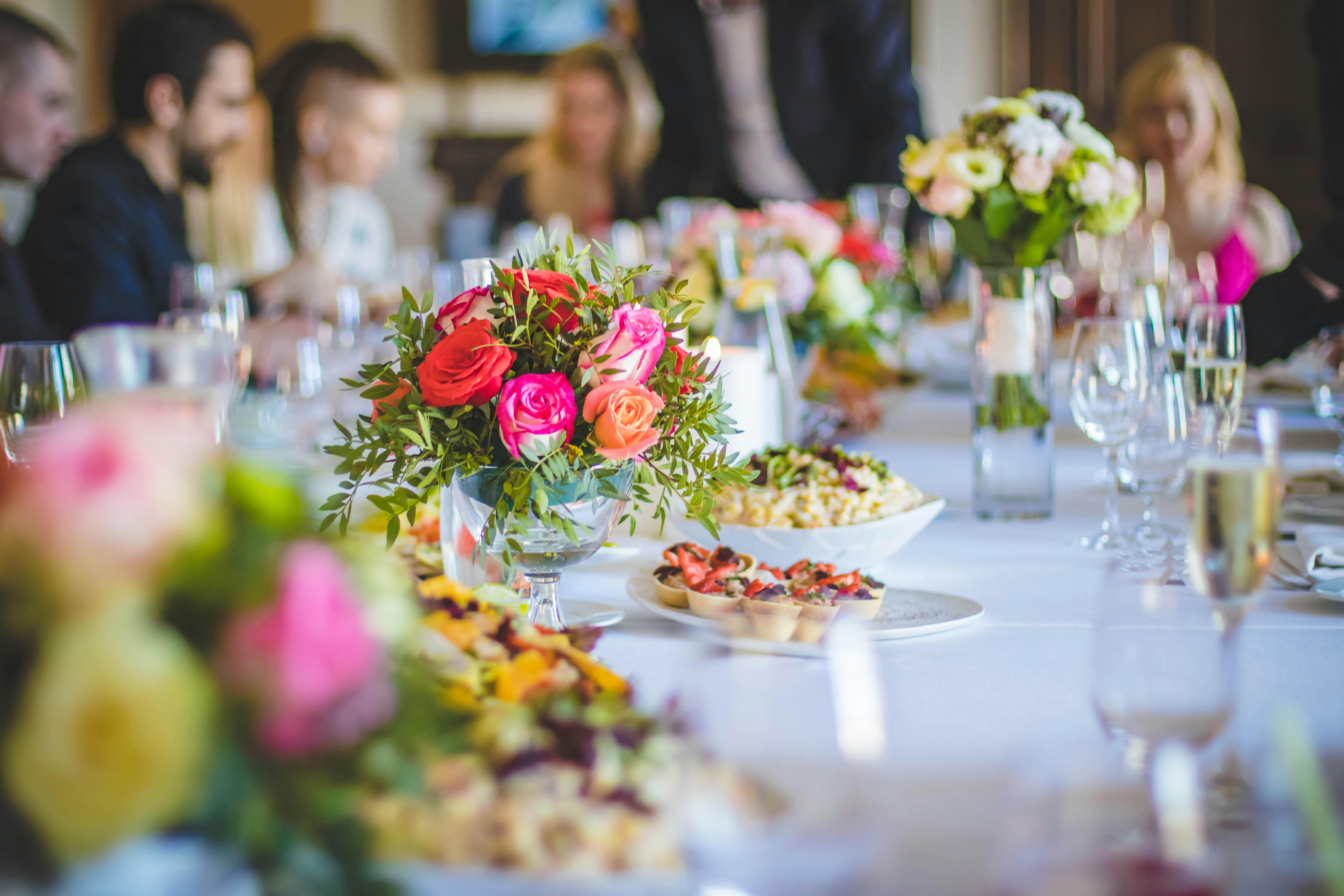 Feestelijk gedekte bruiloftstafel met kleurrijke rozenboeketten, hapjes en champagneglazen in een elegante zaal