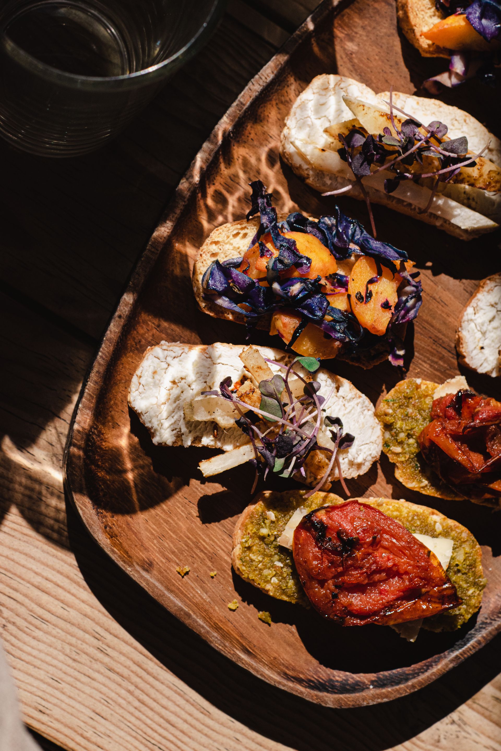 Houten plank met vegan borrelhapjes: hummus, olijven, bruschetta en falafel